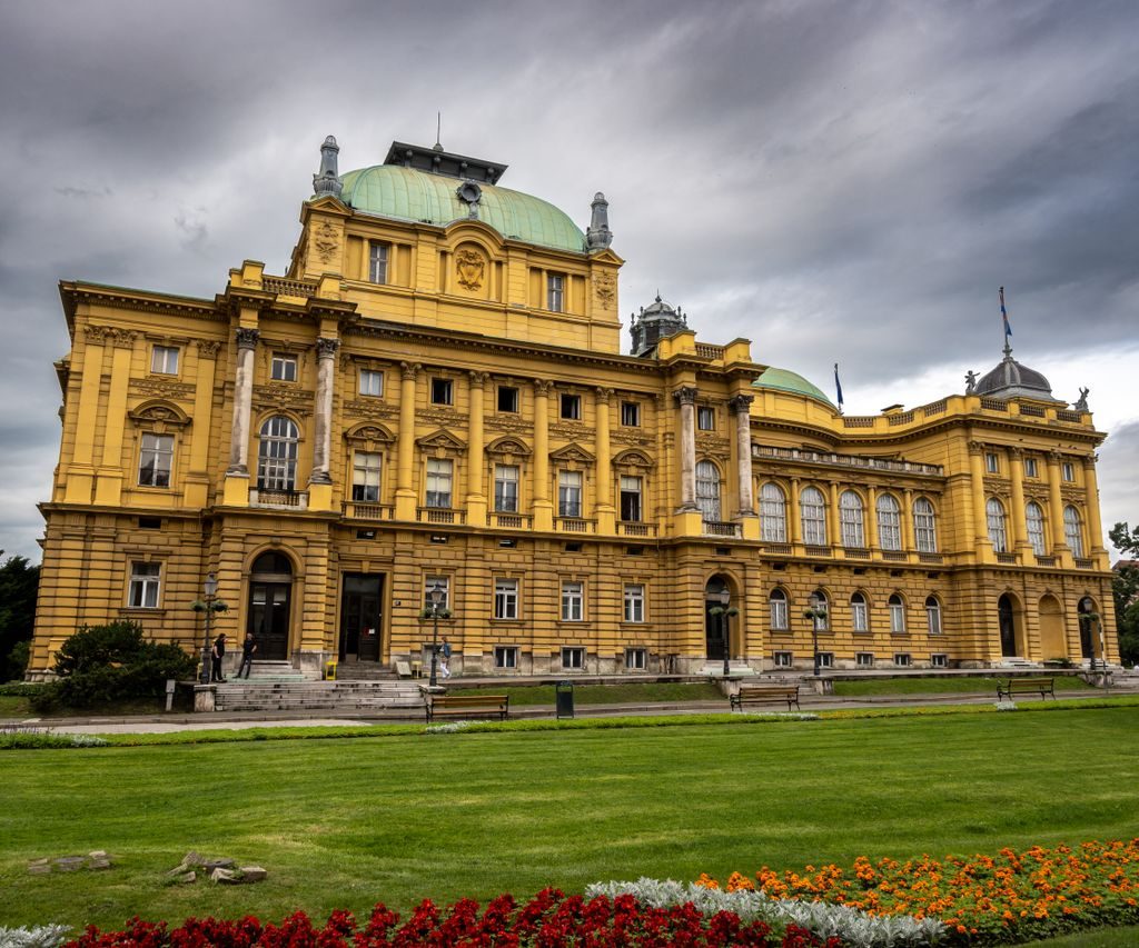 Exterior view of the Neo-Baroque Croatian National Theatre in Zagreb under dramatic clouds.